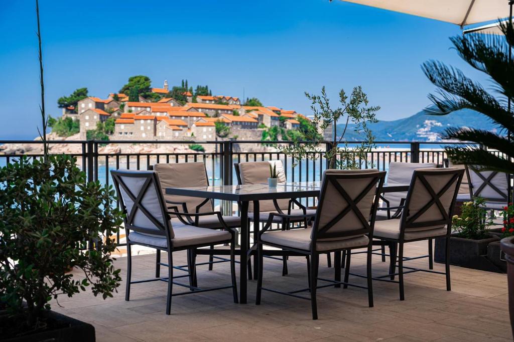 a table and chairs on a balcony with a view at Hotel California by Aycon in Sveti Stefan