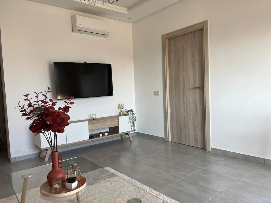 een woonkamer met een tv en een vaas met bloemen bij Luxus-Unterkunft mit Bergblick! in Martil
