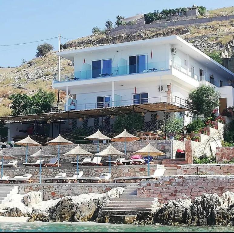 a large white building with umbrellas in front of the water at Sea Breeze Villa in Sarandë