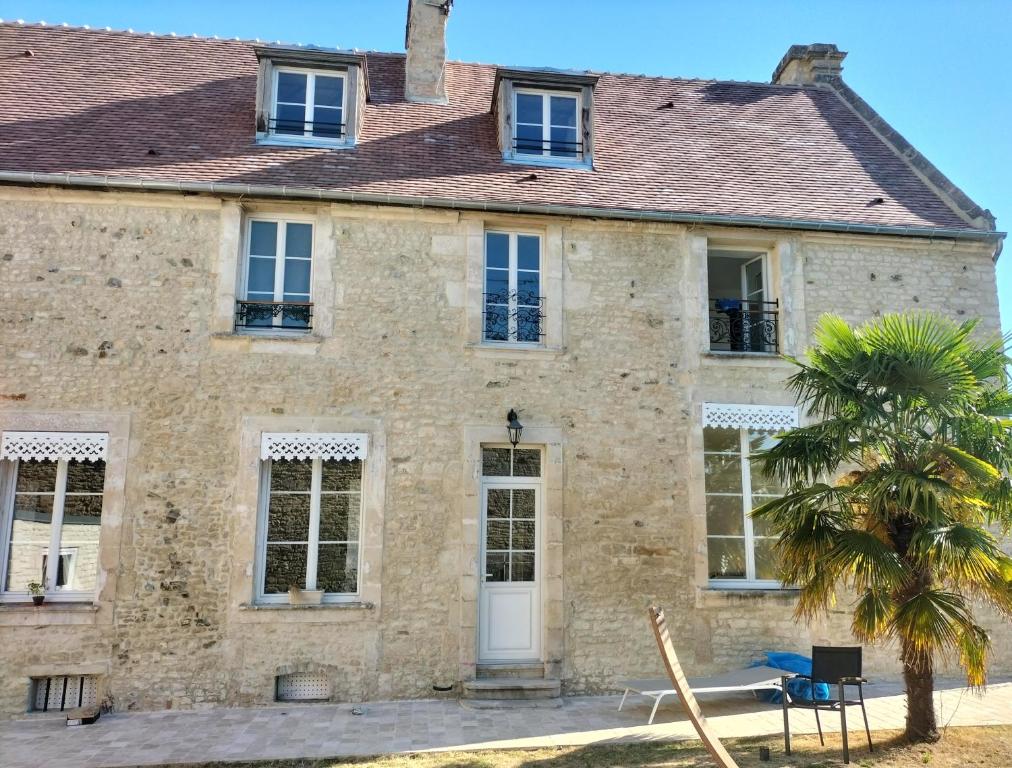 an old stone house with a palm tree in front of it at La maison des remparts in Falaise