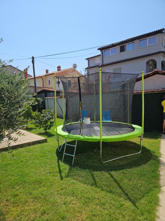 een trampoline in het gras in een tuin bij Apartmani Prodan 2 in Fažana