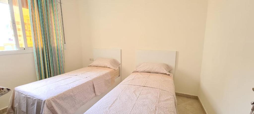 Cette chambre blanche dispose de 2 lits et d'une fenêtre. dans l'établissement tetouan wilaya, à Tetouan