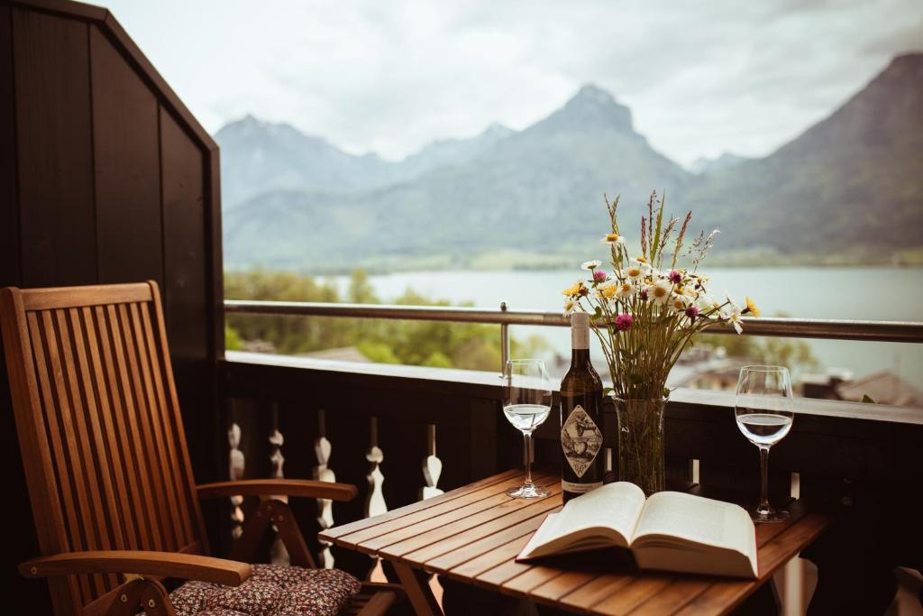 einen Tisch mit einem Buch, eine Flasche Wein und Gläser in der Unterkunft Pension Rudolfshöhe in St. Wolfgang