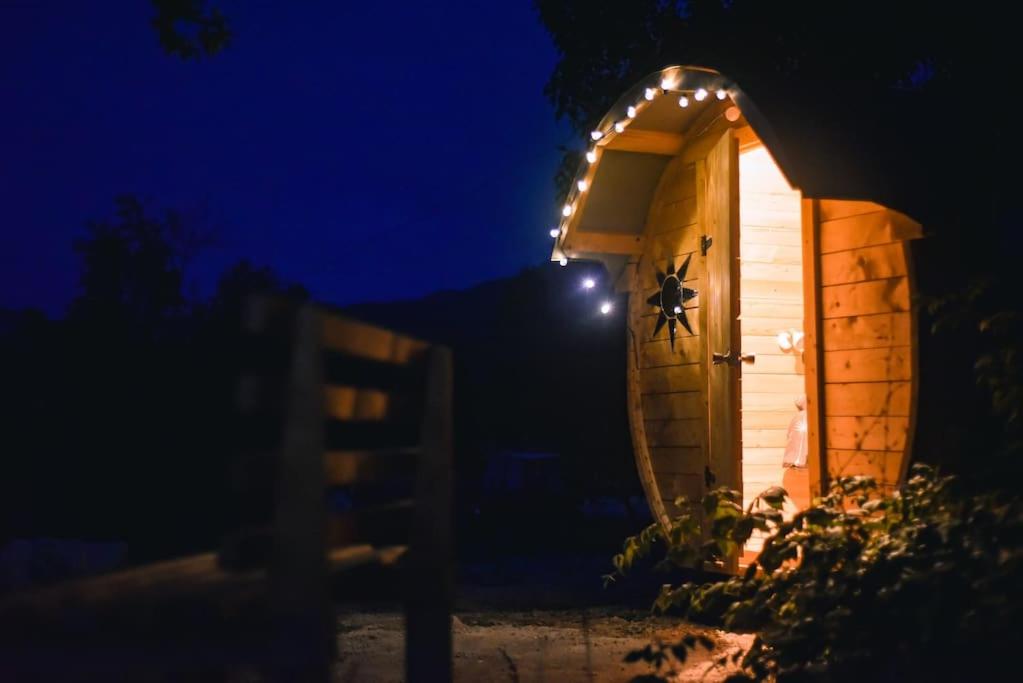 een klein buitenhuis met 's nachts verlichting bij Cozy Barrel in the Hills in Nikšić