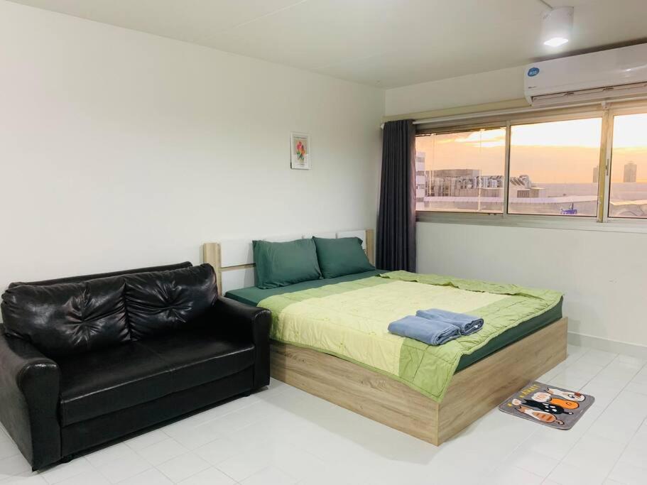 a bedroom with a bed and a black leather chair at Condo popular T8 fl.12 in Thung Si Kan