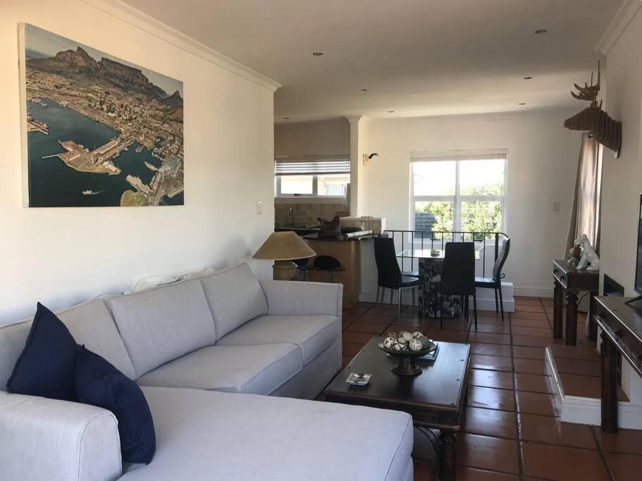 a living room with a white couch and a table at Golf Estate apartment close to the Beach in Cape Town
