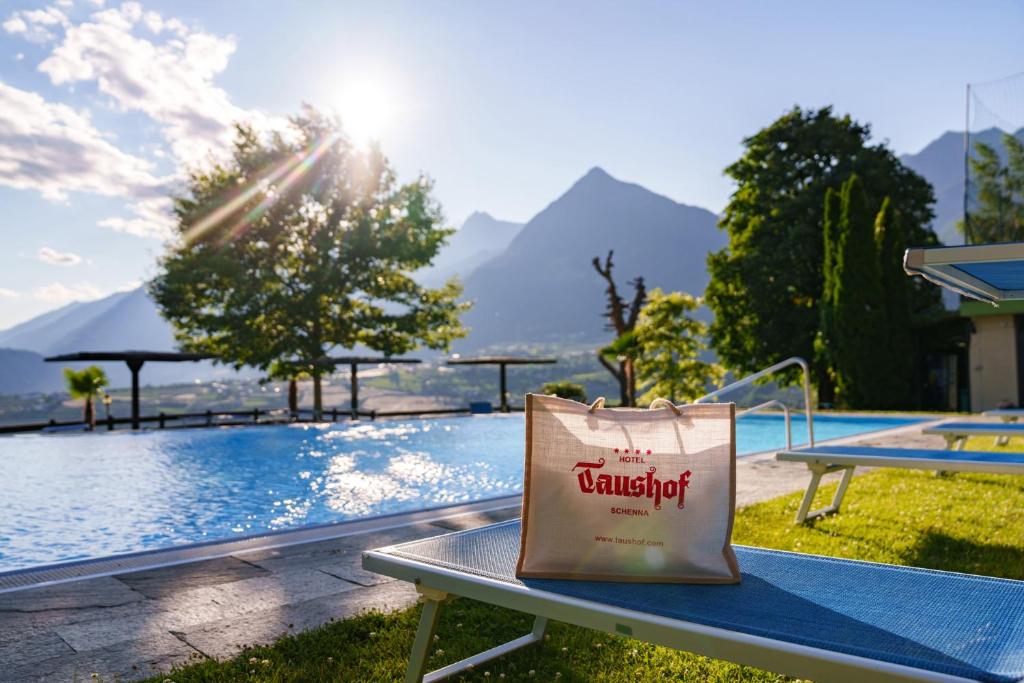 a shopping bag sitting on a bench next to a pool at Taushof in Schenna