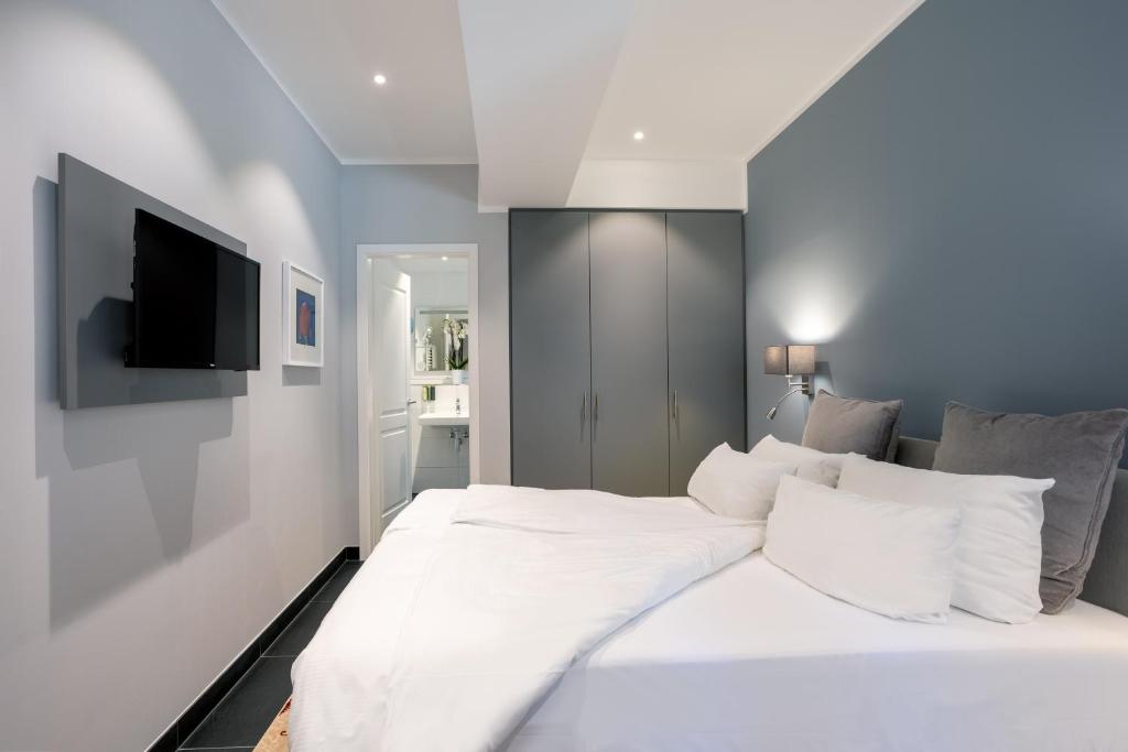Schlafzimmer mit einem weißen Bett und einem Flachbild-TV in der Unterkunft Batschari Palais Baden-Baden in Baden-Baden