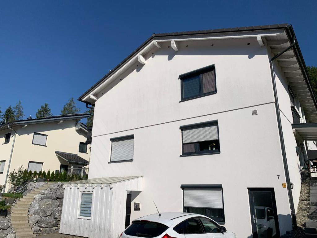 uma casa branca com um carro estacionado em frente dela em Lindenberger Ferientraum em Lindenberg im Allgäu