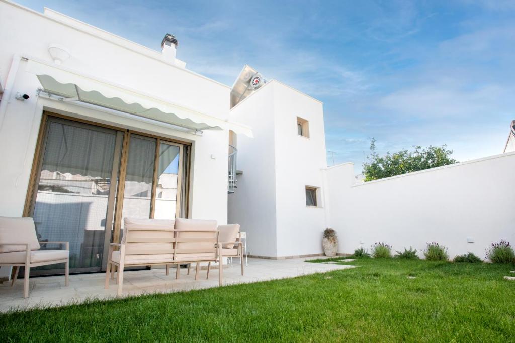 a white house with chairs and a lawn at Ca’ Lezet in Guagnano