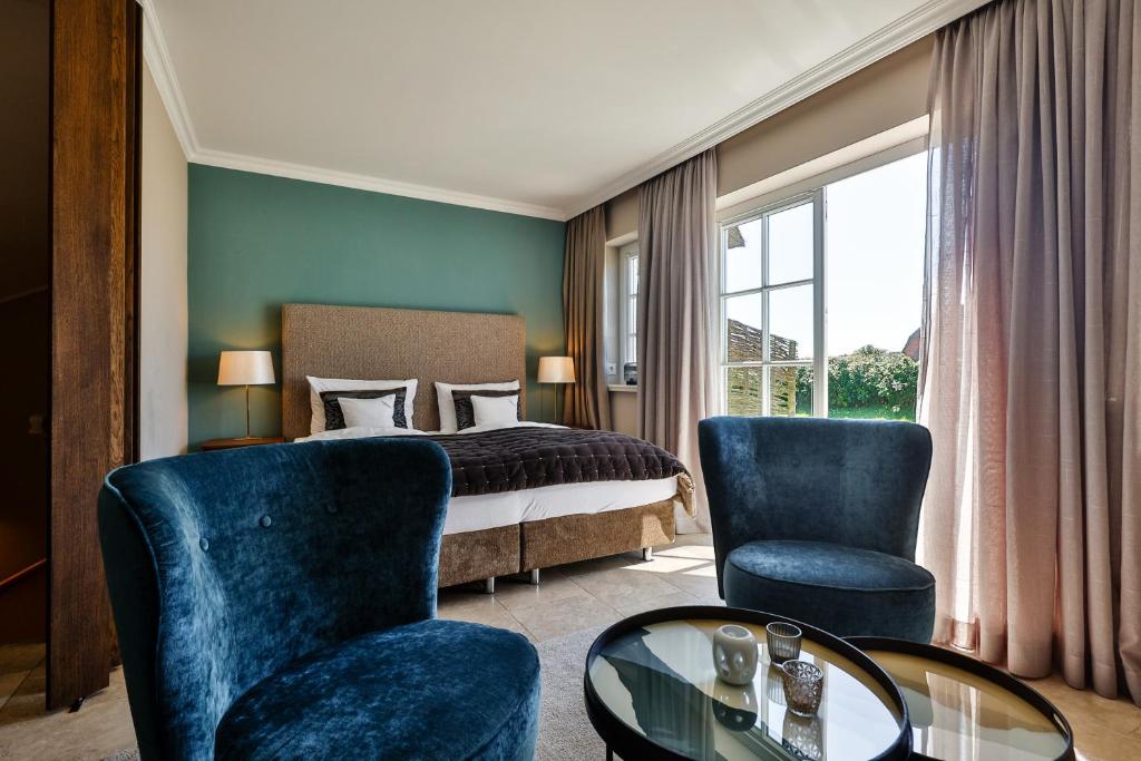 um quarto de hotel com uma cama, uma mesa e cadeiras em Strandvogtei Sylt em Rantum