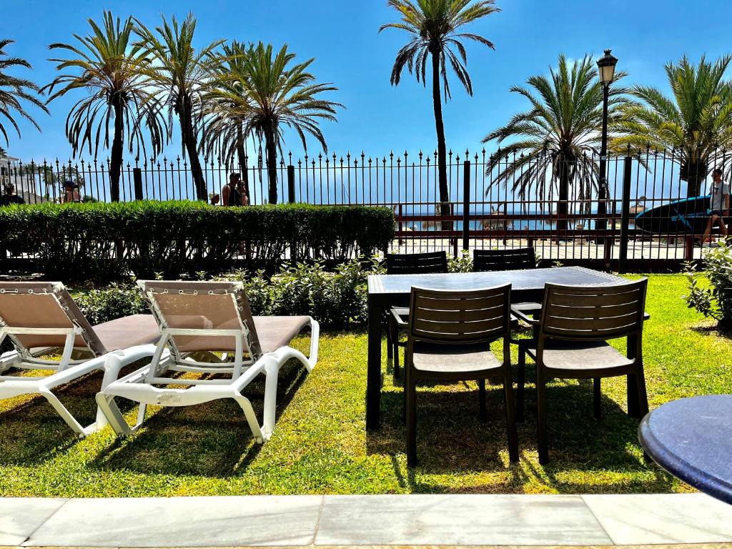 マルベーリャにあるPuerto Banus 2 bedrooms Oceanfront Cの椰子の木の芝生のテーブルと椅子
