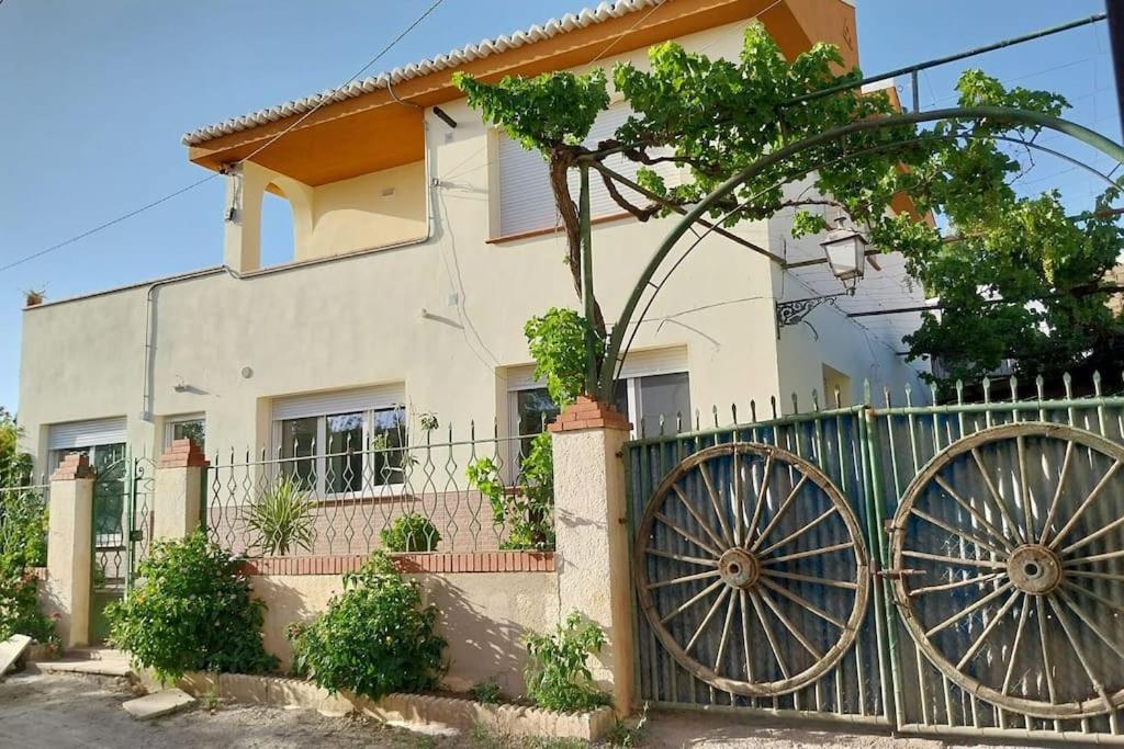 a house with a fence and two large wheels at Casa Anna, Lecrin, Granada in Granada