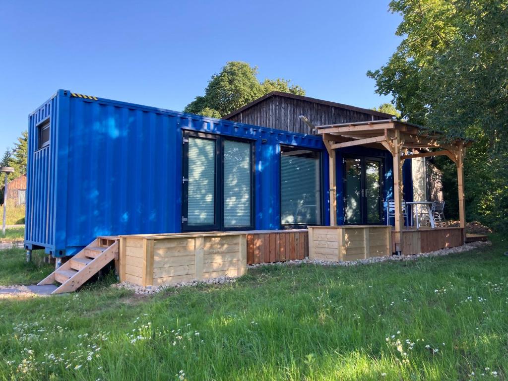 a house with a blue shipping container on a field at Tiny House im Seecontainer mit Parkplatz, Glasfaser, Netflix, Veranda und gehobener Ausstattung in Coburg