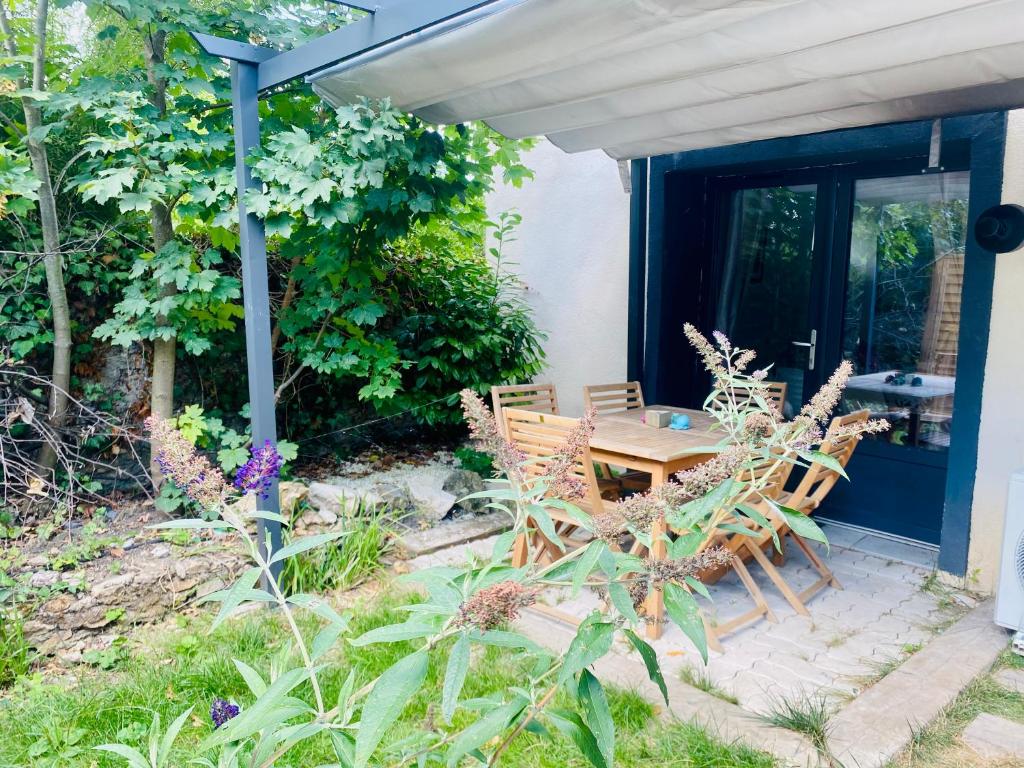 um pátio com uma mesa de madeira e cadeiras num jardim em Duplex climatisé avec une terrasse sur jardin em Montmorency