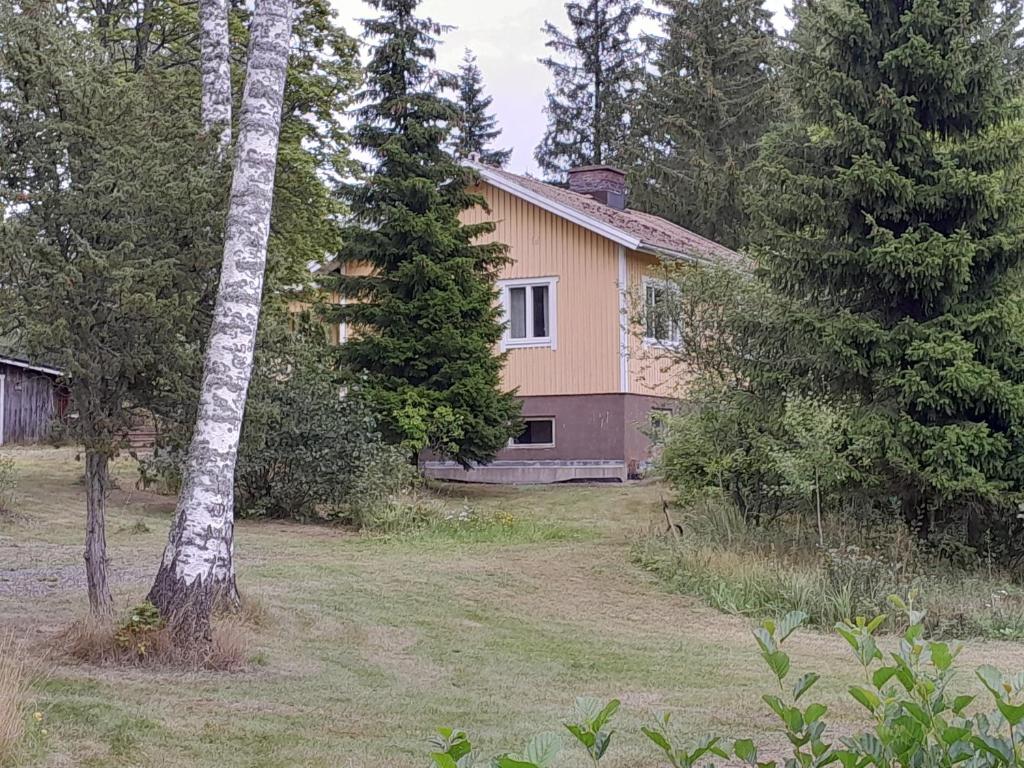 a house in the middle of a yard with trees at Ugglebo, stuga in Nauvo