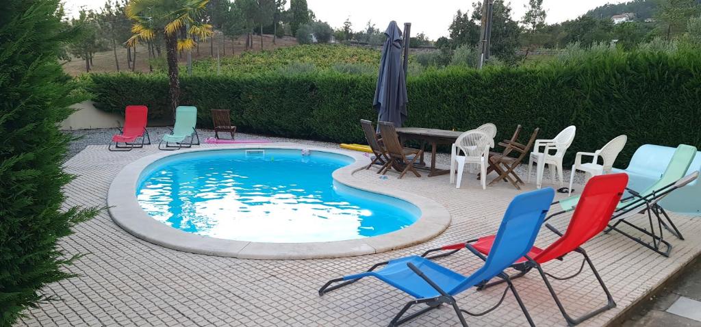 um grupo de cadeiras e uma piscina com cadeiras e um guarda-sol em Vivenda do relaxo em Freiria