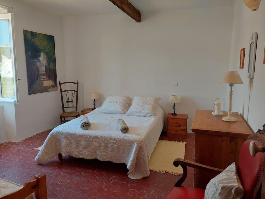 um quarto com uma cama com uma colcha branca em Maison de César em Saint-Saturnin-dʼApt