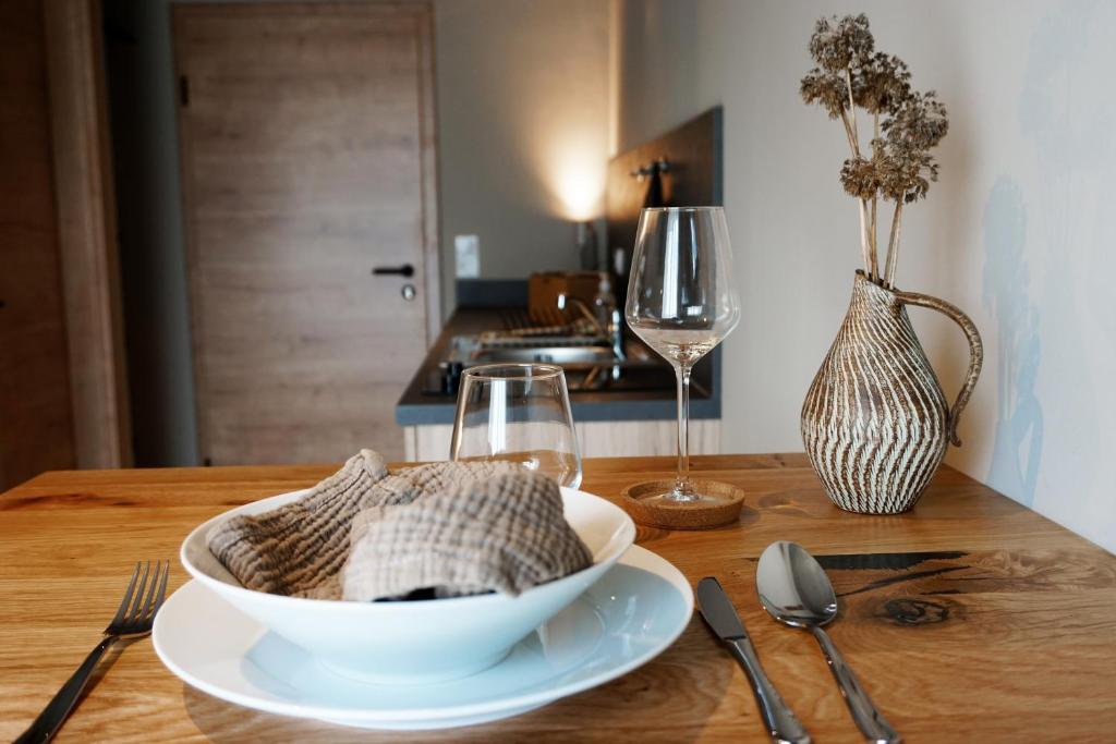 a wooden table with a white bowl and a wine glass at Talbach Apartments in Buchen