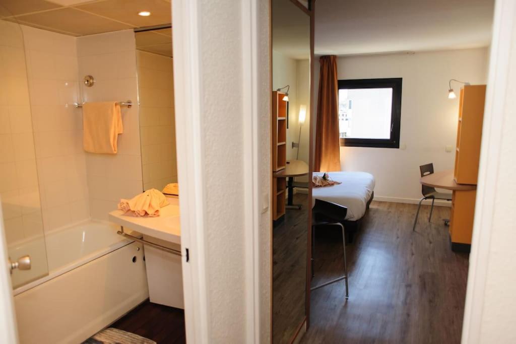 a hotel room with a bed and a bathroom at Élégant studio proche Paris, disponible 24&#47;7. in Pantin