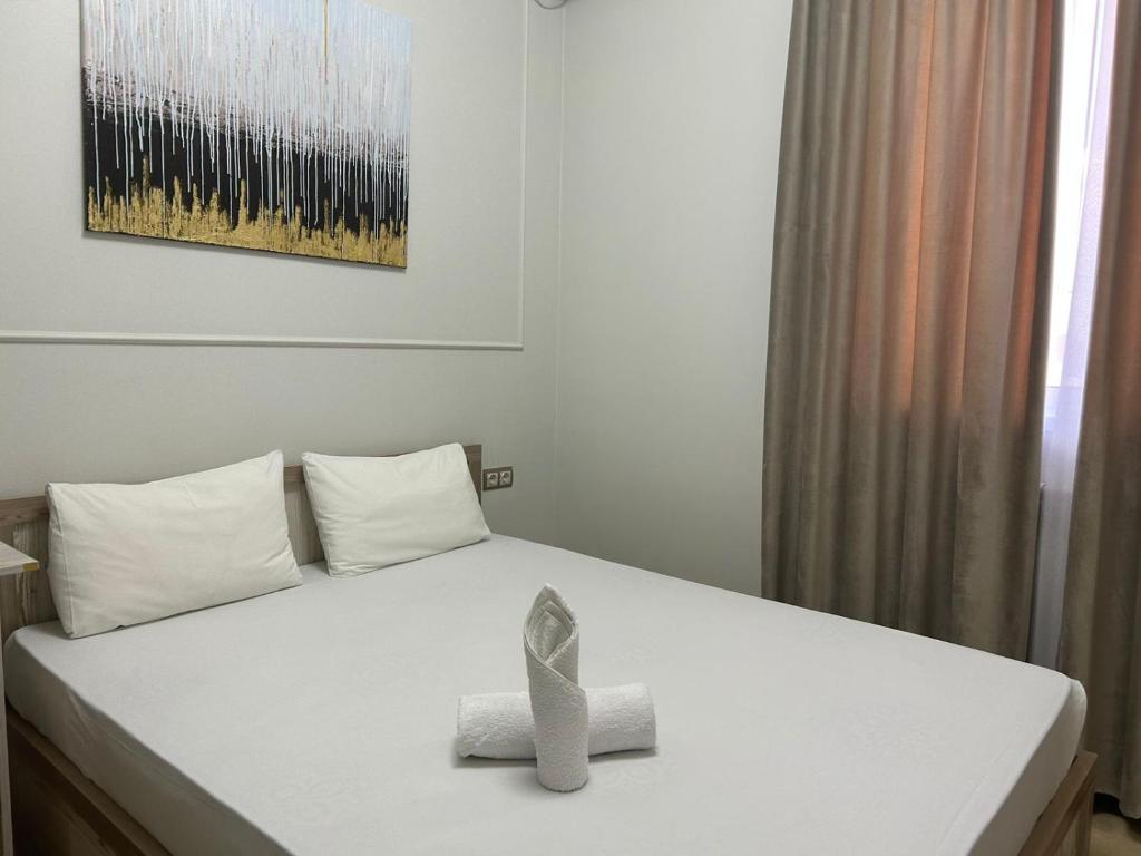 Una cama blanca con una caja encima. en Hotel Bereke, en Atyraū