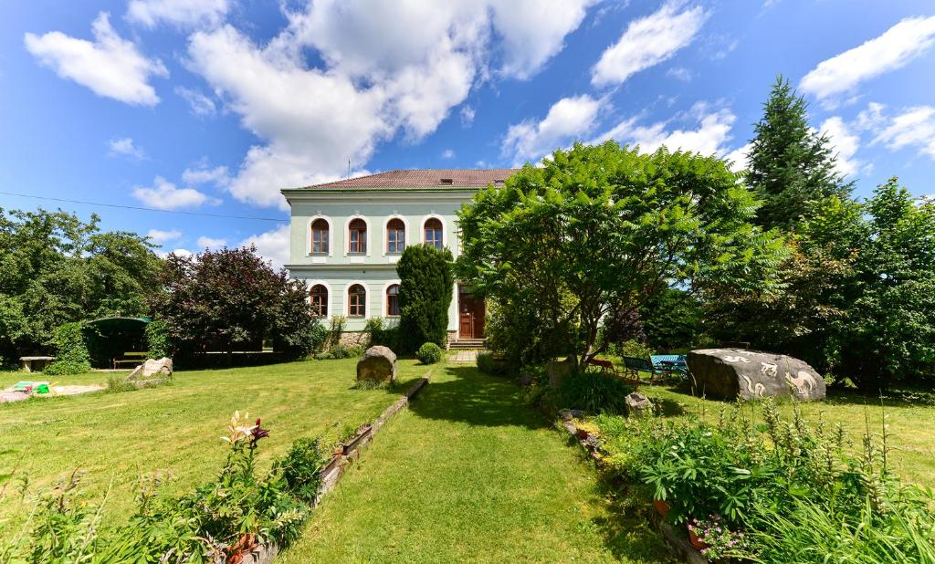 una casa grande en un campo de hierba con un árbol en Penzion Medvedi Paseka, en Nová Bystřice