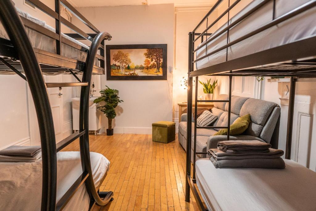 ケベック・シティーにあるAuberge de la paixの二段ベッド2台とソファが備わる客室です。