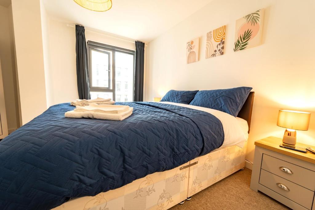 a bedroom with a bed with blue sheets and a window at Spacious Apartment in Woking Town Centre in Woking