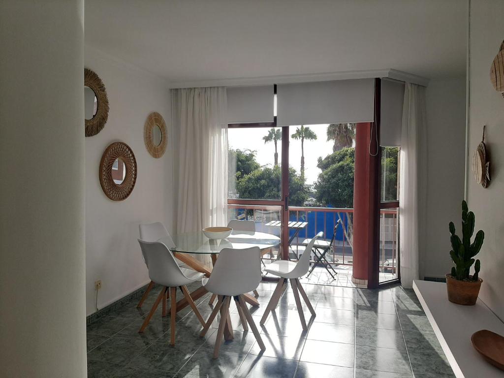 una sala da pranzo con tavolo in vetro e sedie bianche di El apartamento de MATITA - free parking and beach a Telde