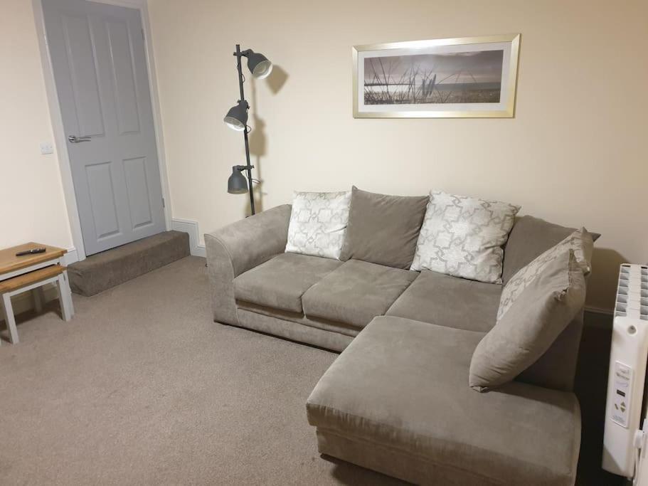 uma sala de estar com um sofá e uma mesa em large comfortable 1st floor apartment with private yard em Longtown