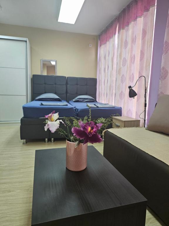 a room with two beds and a table with flowers at LENI apartman u centru Zajecara in Zaječar