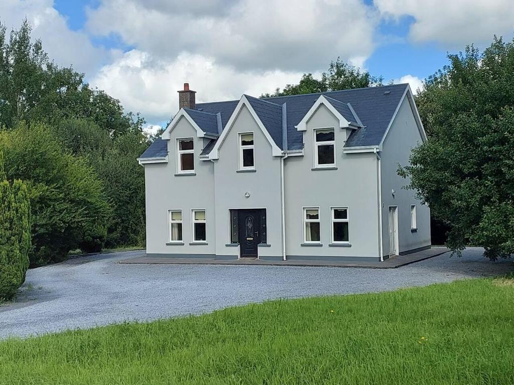 une grande maison blanche avec une allée. dans l'établissement Home in Ennis, à Ennis