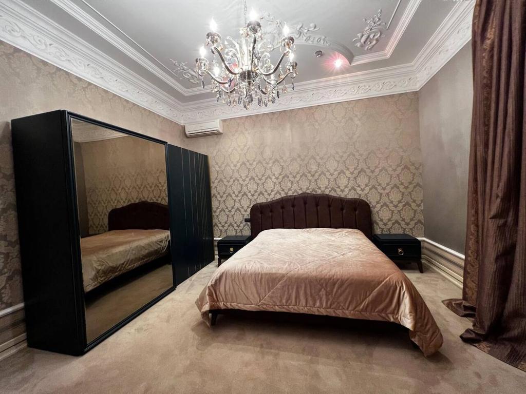 Schlafzimmer mit einem Bett, einem Spiegel und einem Kronleuchter in der Unterkunft Marriott Absheron 2 bedroom apartment in Baku