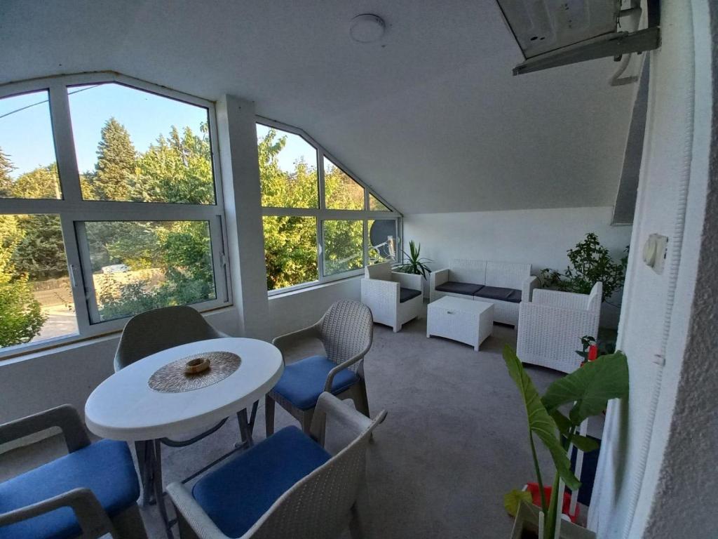 een woonkamer met een tafel, stoelen en ramen bij Vila Nastovski in Veles
