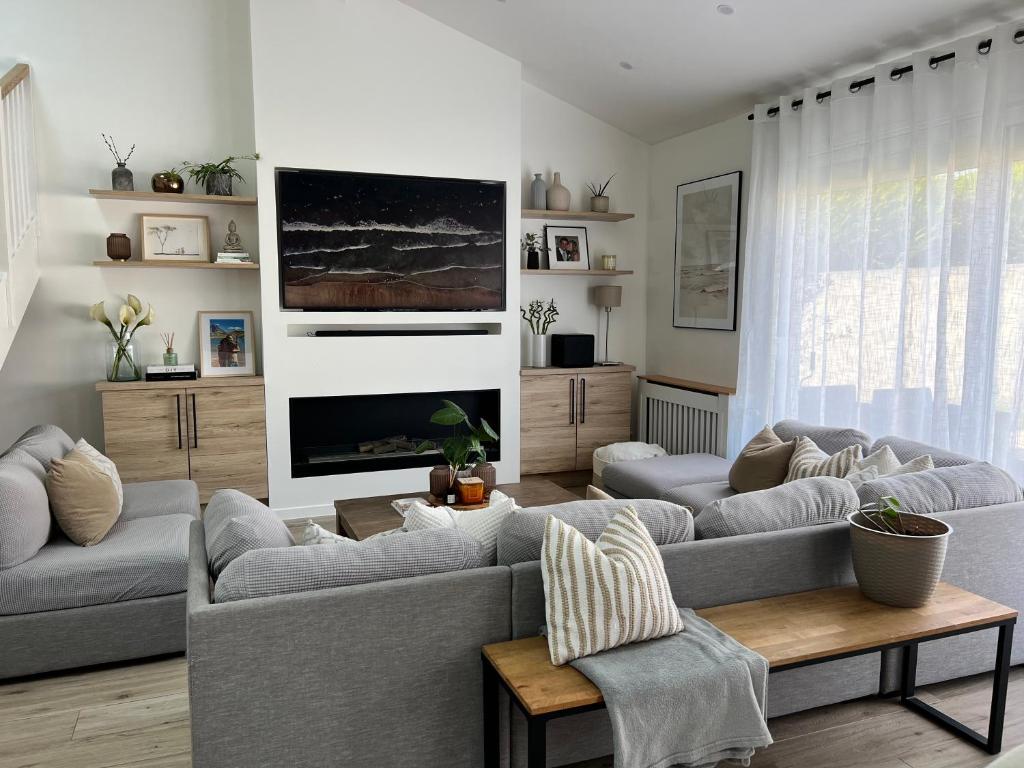 ein Wohnzimmer mit 2 Sofas und einem TV in der Unterkunft Maison Paris Jeux Olympiques in Othis
