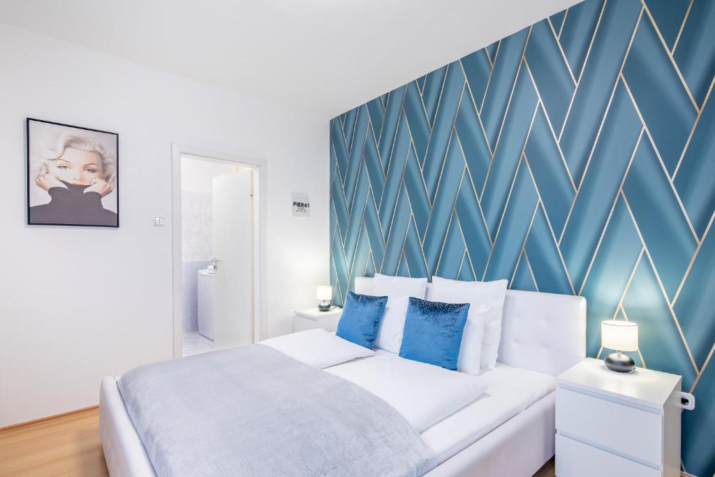 Una cama blanca en una habitación con una pared de acento azul. en Two bedrooms apartment with free garage in the downtown, en Budapest