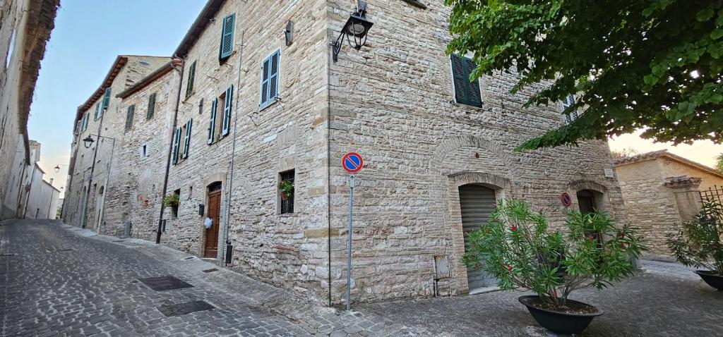 - un grand bâtiment en pierre avec une rue en face dans l'établissement La casa di Francesco, à Sassoferrato