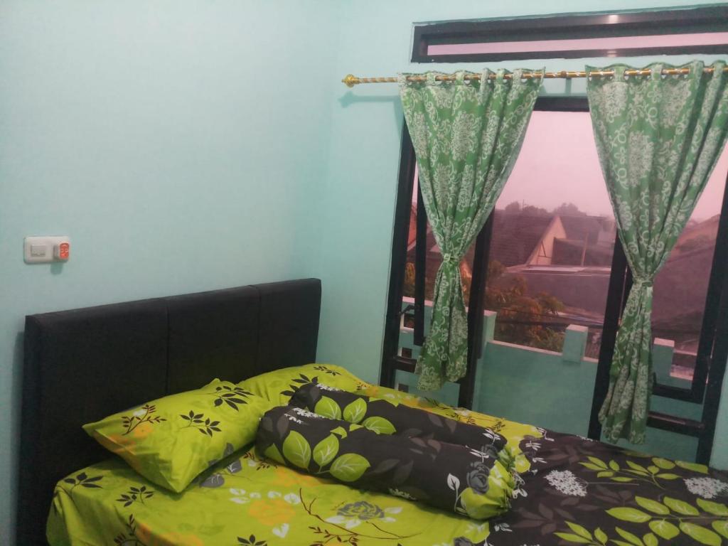 Schlafzimmer mit einem Bett und einem Fenster mit Vorhängen in der Unterkunft Guest House Murah -homestay - Kos harian 