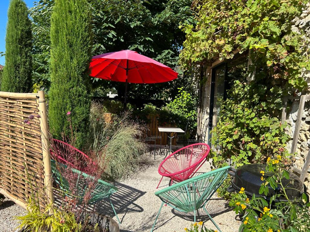 um guarda-sol vermelho num jardim com cadeiras e uma mesa em La Grange de la Maison des chats em Saint-Amans-du-Pech