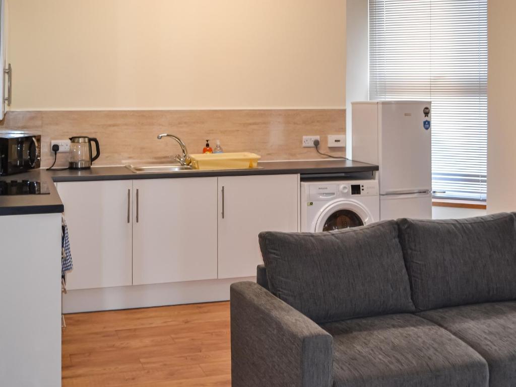 a kitchen with a couch and a sink and a refrigerator at Harbour Apartment in Nairn