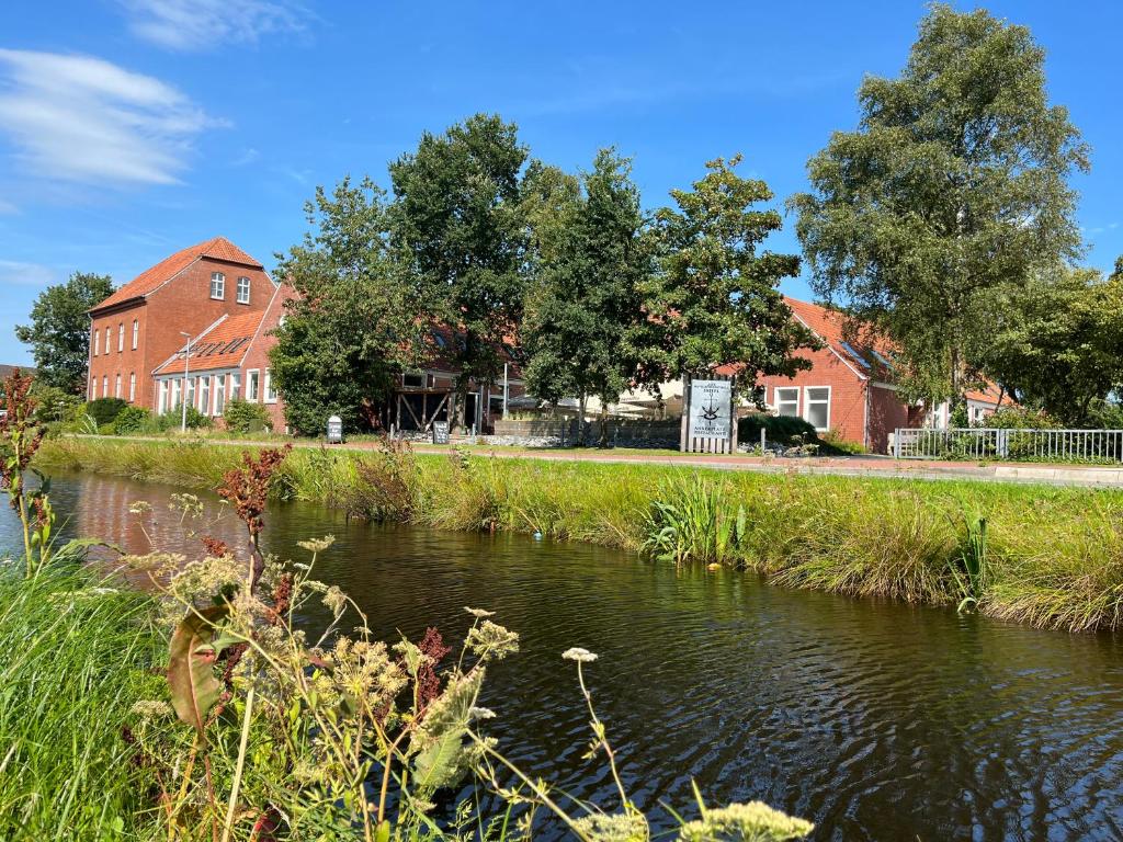 een rivier voor sommige huizen en bomen bij Hotel Alte Navigationsschule in Rhauderfehn