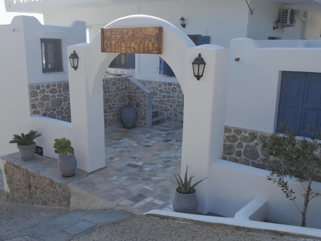 a white building with a gate and potted plants at George's Home Platy Gyalos in Kalymnos
