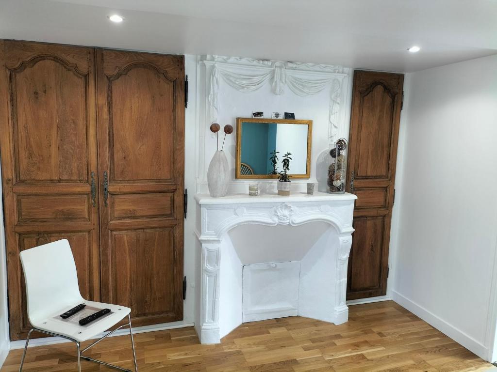 un camino bianco in una stanza con specchio e sedia di Chambre d hôte a Falaise