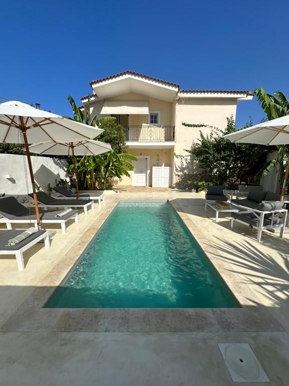 a swimming pool with chairs and umbrellas in front of a house at KATINA'S DREAM HOUSE IN PELOPONNESE in Aigio