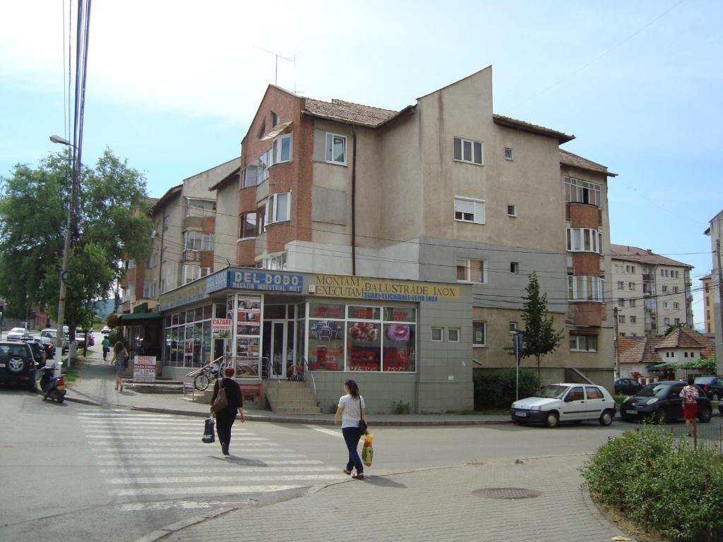 two people crossing a street in front of a building at Apartament Del Dodo in Alba Iulia