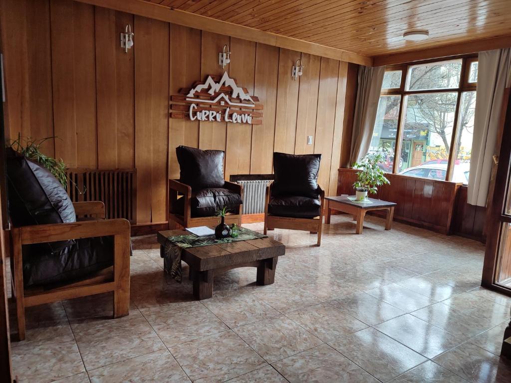 a lobby with chairs and a table and a sign at Hotel Curru Leuvu in San Carlos de Bariloche