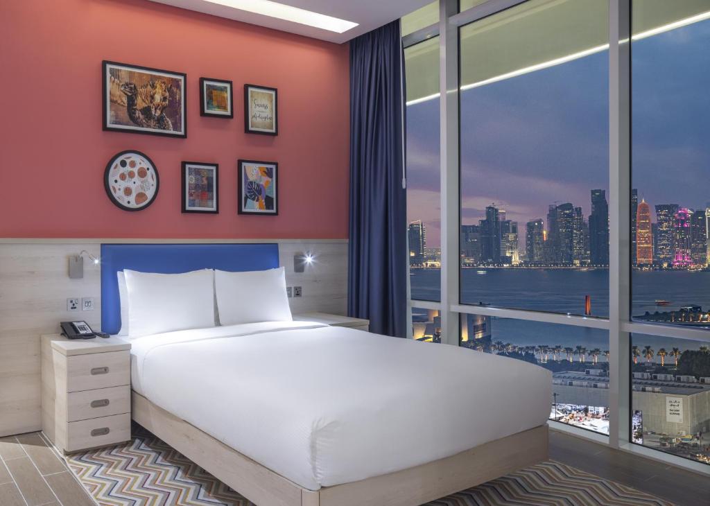 a bedroom with a large bed and a large window at Hampton By Hilton Doha Old Town in Doha