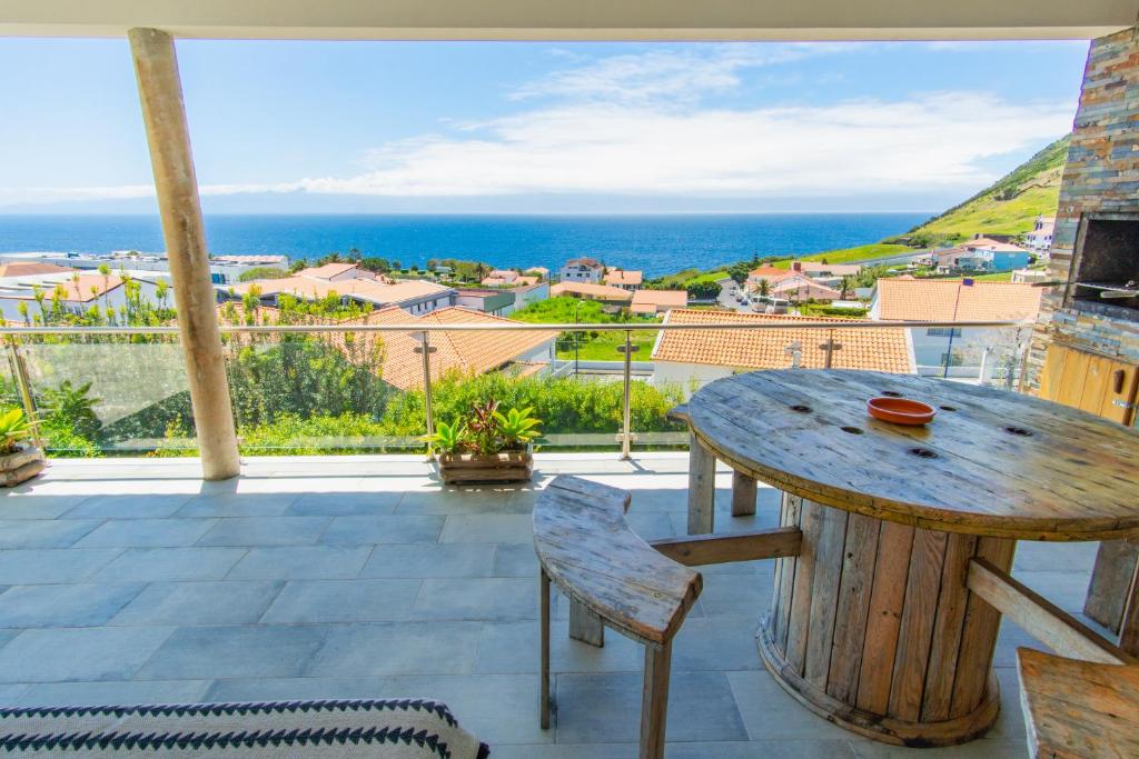 a table and chairs on a balcony with a view of the ocean at Blue Planet São Jorge Azores - RRAL nº 1341 in Velas