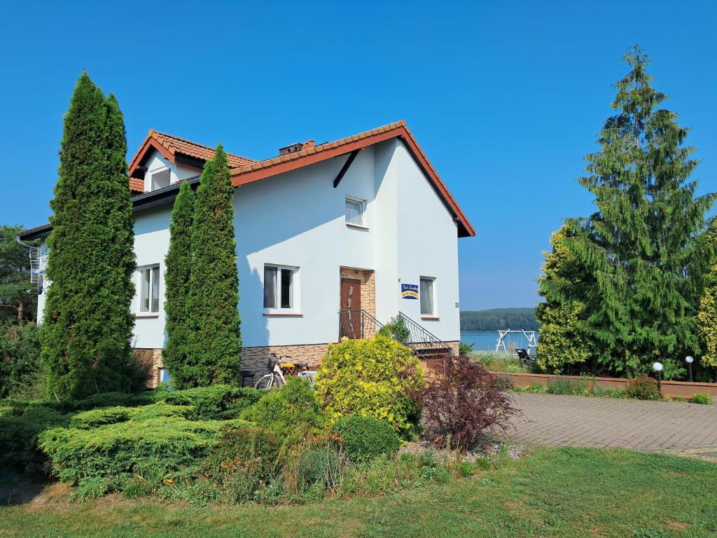 a house with trees in front of the water at Posiadłość Nad Zatoką in Ryn
