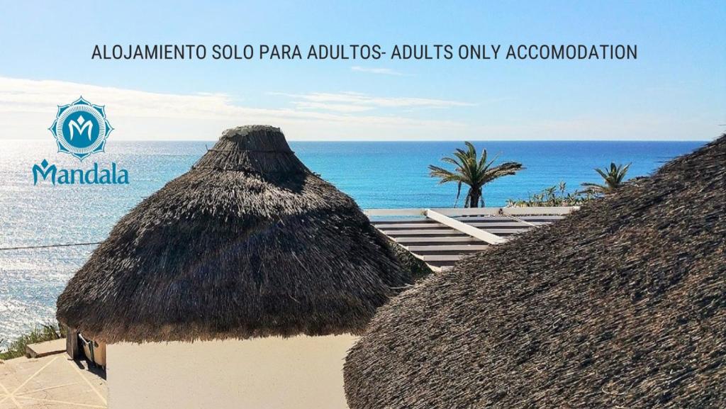 dos cabañas de paja en una playa con el océano en Mandala Bungalows - Adults Only, en Los Caños de Meca